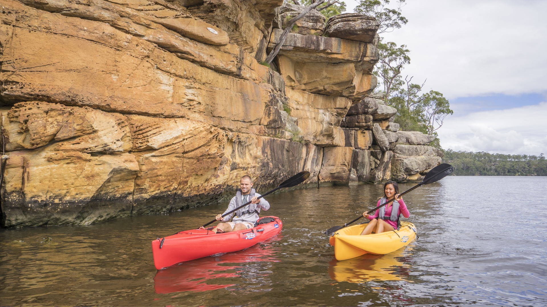 Two people kayaking next to a large rock
